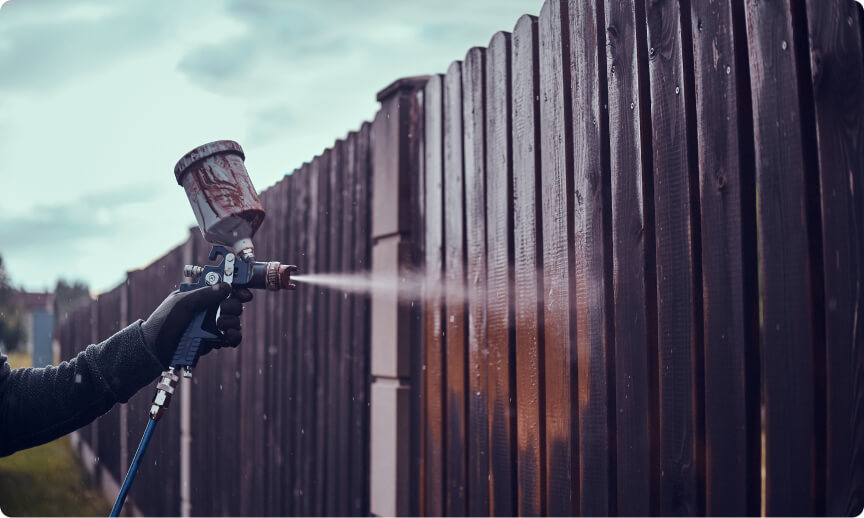 applying paint old fence using airbrush his garden