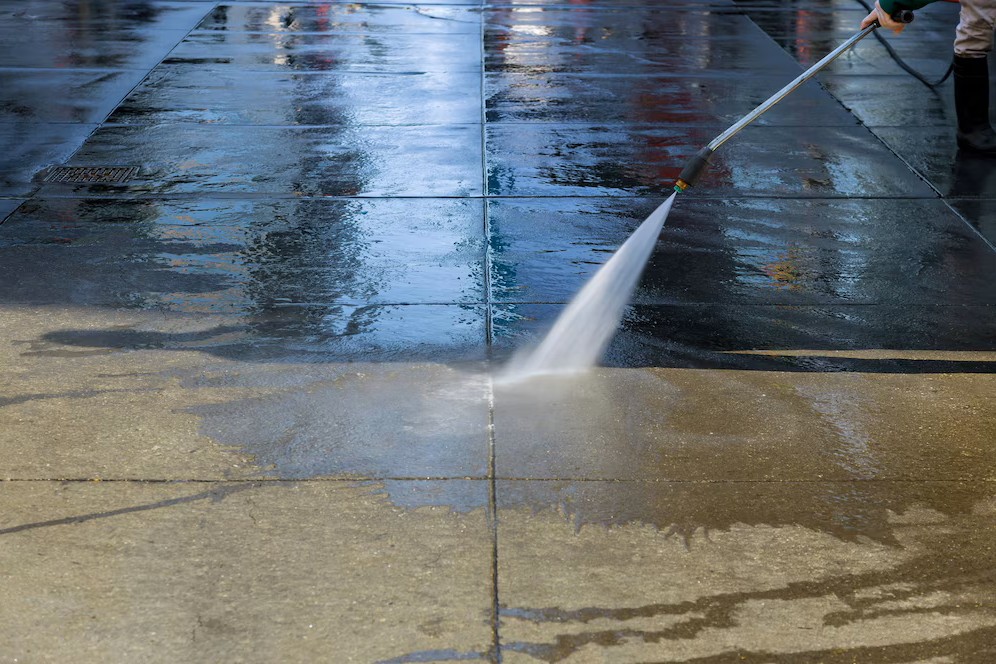 worker pressure washing pavement asphalt